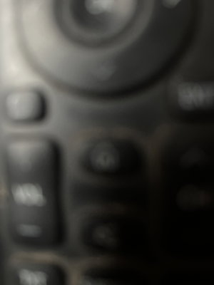Blurry close-up of remote control buttons and dial.