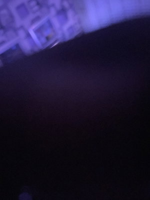 Dark blurry room with purple lighting and framed wall.