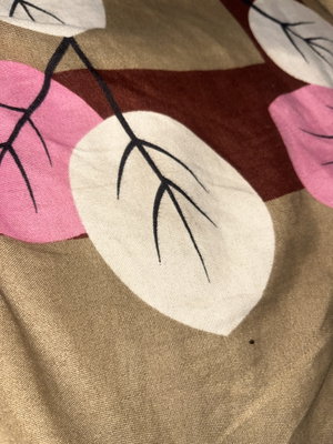 Close-up of patterned fabric with pink, white, and brown leaf designs.