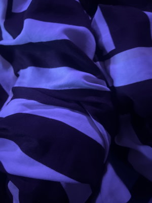 Close-up of black and white striped fabric under purple lighting.