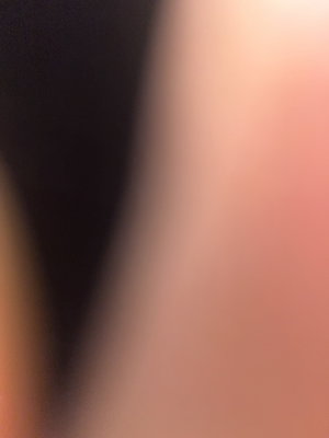 Blurred close-up of skin and dark fabric, indistinct features.