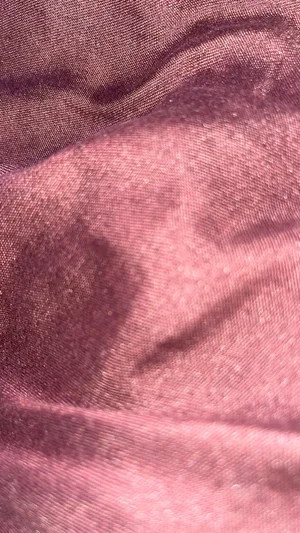 Close-up of pink fabric with soft folds and subtle sheen.