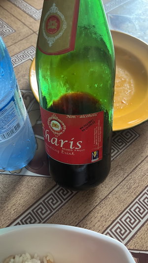Table with sparkling drink bottle, water, rice, food.