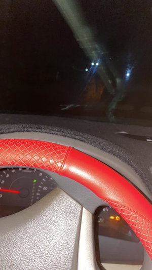 Nighttime car interior with red steering wheel.