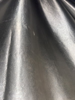 Close-up of shiny silver satin fabric with folds.