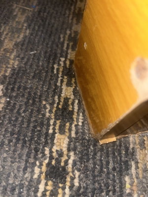 Close-up of patterned carpet next to wooden furniture leg.