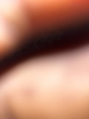 Blurred close-up of skin and dark hair, indistinct features.