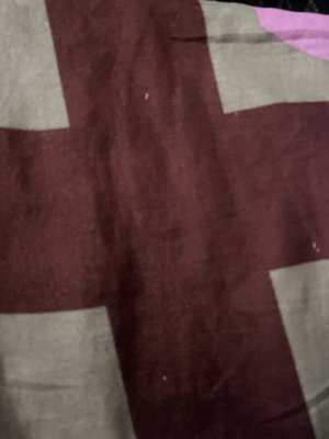 Close-up of a maroon and beige patterned fabric, possibly a blanket or bedsheet.