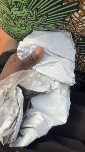 Hand holding white plastic bag on patterned fabric.