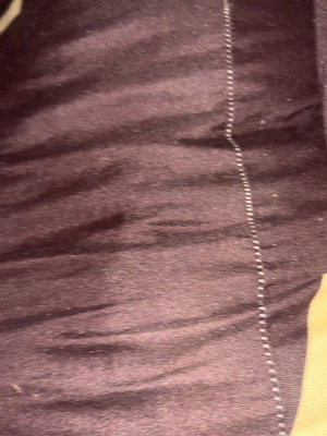 Close-up of dark purple fabric with white stitching.