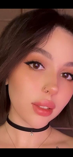 Woman with dark hair and makeup wearing choker necklace in close-up selfie.