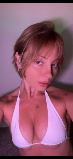 Woman with short hair in white bikini top, indoor setting, facing camera.
