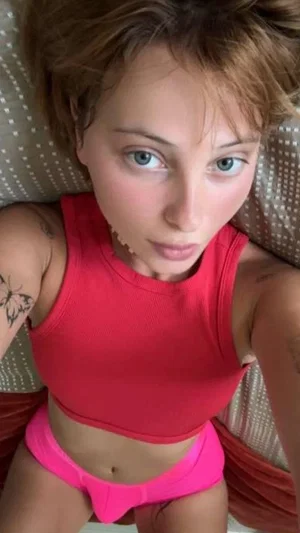 Woman with short hair in red crop top and pink underwear lying on patterned surface.