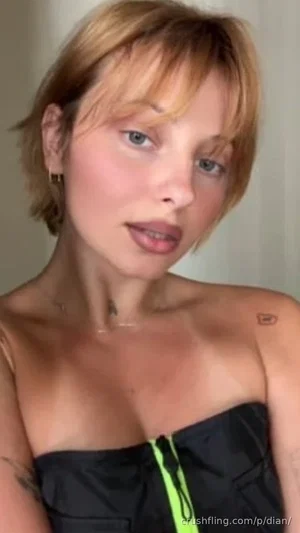 Woman with short blonde hair in black strapless top, indoor setting.