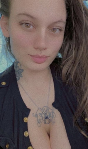 Buxom brunette with neck tattoos in black button top.