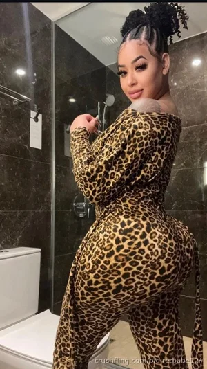 Woman in leopard print bodysuit posing in bathroom mirror selfie.