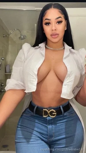 Woman with long black hair in white shirt and jeans, posing in bathroom.