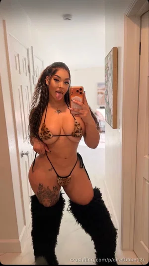 Woman in leopard-print lingerie and black thigh-high boots posing in a hallway mirror selfie.