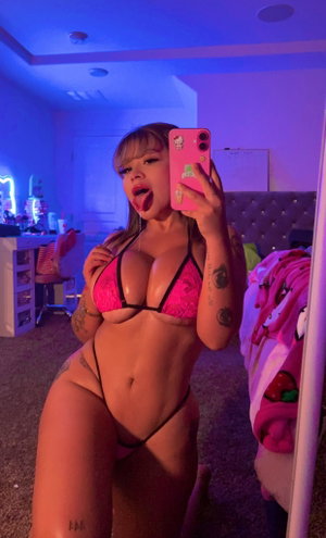 Curvy woman in pink string bikini in neon bedroom.