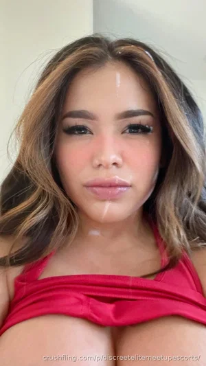 Woman with wavy hair wearing red top, indoors, close-up selfie.