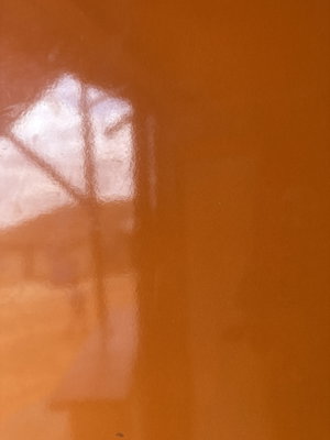 Frosted orange surface with faint reflection of window or structure.