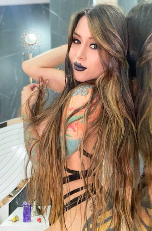 Curvy woman with tattoos in black strappy lingerie in bathroom.