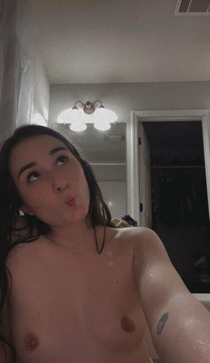 Brunette topless in bathroom mirror selfie.