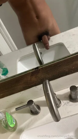 Shirtless man in bathroom mirror selfie, showing torso above sink.