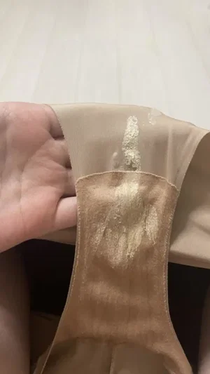 Hand holding stained beige underwear close up.