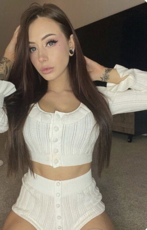 Woman with long brown hair wearing white outfit indoors.