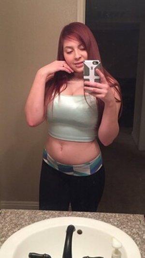 Redhead woman in crop top and leggings in bathroom.