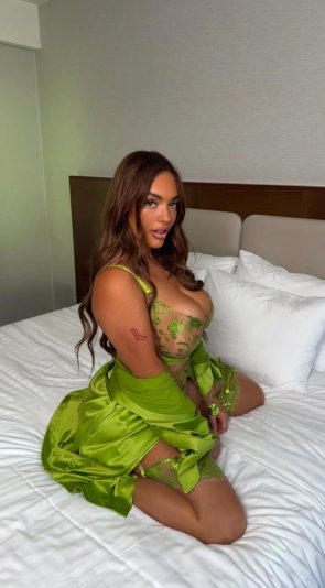 Woman with long brown hair in green lingerie on bed