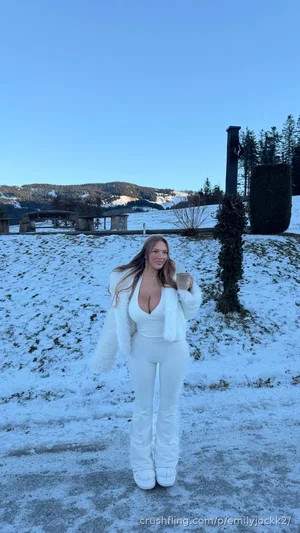 Woman in white outfit and fur coat standing in snowy outdoor setting.