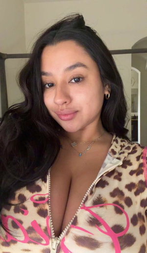 Woman with long dark hair wearing leopard print top indoors.