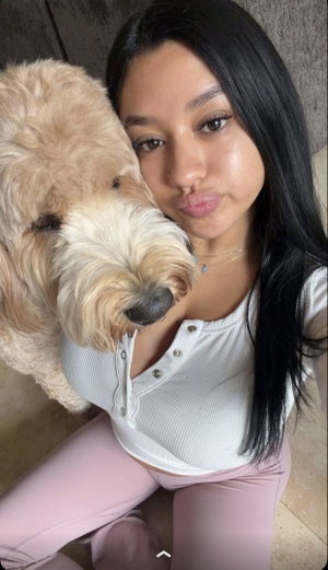 Woman with long black hair posing with a dog indoors.