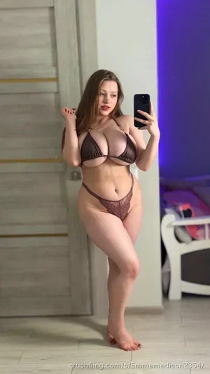 Woman in brown lingerie posing for mirror selfie in bedroom.