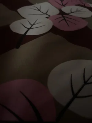 Close-up of fabric with pink and white leaf patterns on dark background.