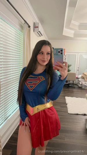 Woman in Supergirl costume taking mirror selfie in bedroom.