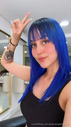 Woman with bright blue hair and black tank top making peace sign indoors.