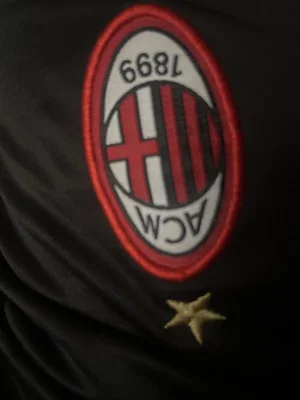 Black fabric featuring AC Milan logo and small gold star below.