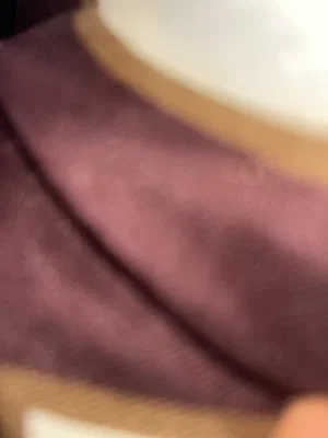 Close-up of maroon fabric with beige trim, possibly clothing or bedding.