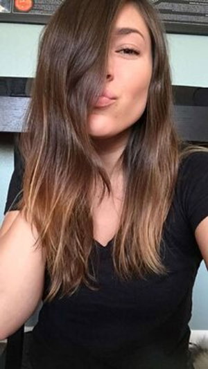 Brunette woman in black v-neck top indoor selfie.