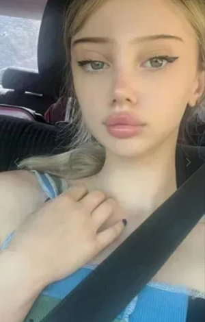 Blonde woman in plaid top taking car selfie.