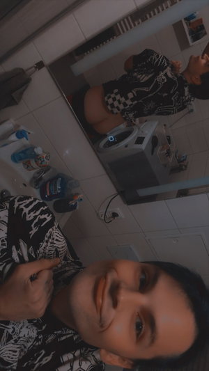 Man in patterned shirt taking bathroom selfie.