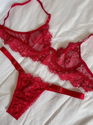 Red lace lingerie set on white fabric background.