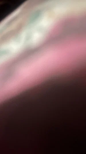 Blurred close-up of pink fabric, possibly skin or clothing, with indistinct background.