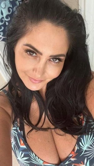 Woman with dark hair in a floral top, close-up selfie indoors.