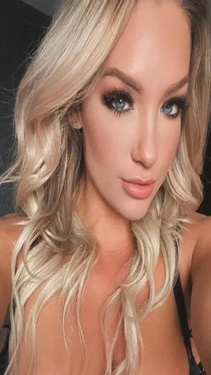 Blonde woman in black top, indoor selfie.