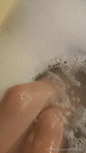 Close-up of legs in bubbly bathwater, skin partially submerged.