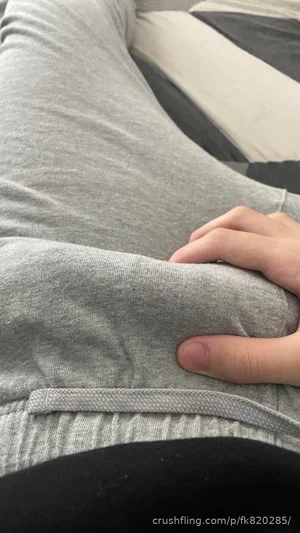 Person in gray sweatshirt and black pants, hand on hip, indoor setting.